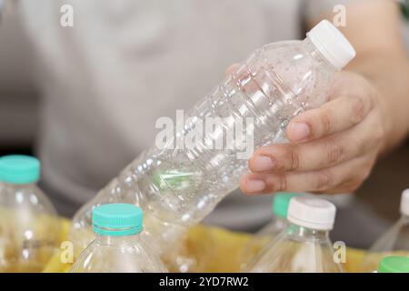 Casa riciclare eco-green zero Concept uomo che lancia bottiglie di plastica vuote in un cestino con sacchetti per rifiuti gialli a casa Foto Stock