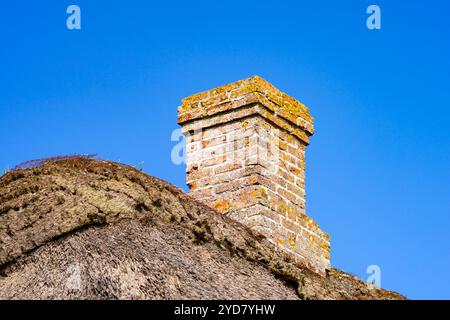 Vecchio camino in mattoni sul tetto di una casa contro il cielo blu Foto Stock