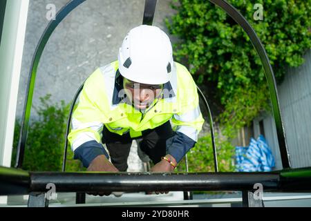 Il tecnico sale una scala sul tetto per controllare l'installazione dei pannelli solari Foto Stock