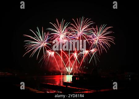 Fuoco d'artificio. Splendidi fuochi d'artificio colorati sulla superficie dell'acqua con uno sfondo nero pulito. Festa divertente e gara di sparatorie Foto Stock