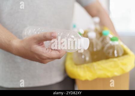 Casa riciclare eco-green zero Concept uomo che lancia bottiglie di plastica vuote in un cestino con sacchetti per rifiuti gialli a casa Foto Stock