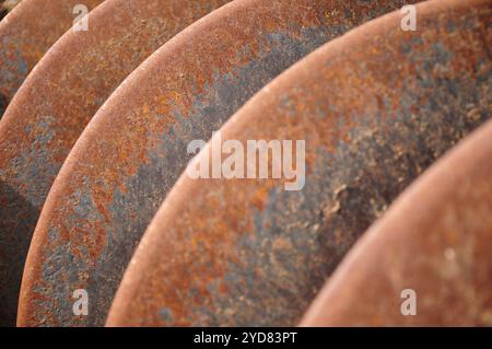 Primo piano di dischi in metallo arrugginito di fila con texture e toni terrosi Foto Stock