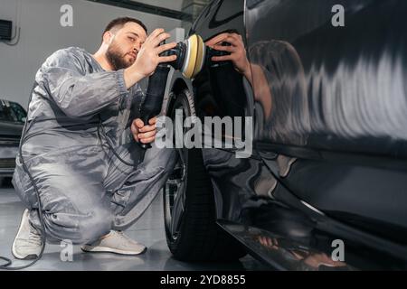 Lucidatrice per auto da lavoro con speciale smerigliatrice e cera dai graffi presso la stazione di servizio dell'auto. Dettagli e principali dell'auto professionali Foto Stock
