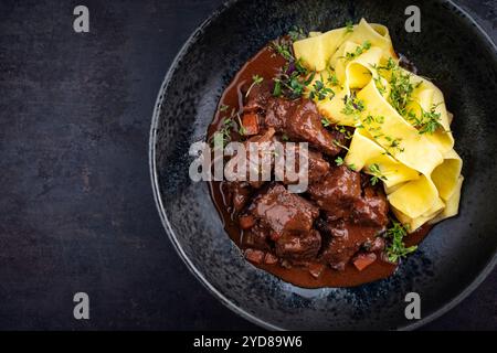 Tradizionale ragù di veleno brasato tedesco con verdure e tagliatelle in salsa dolce e piccante al cioccolato al vino rosso servito come vista dall'alto in un nordico Foto Stock