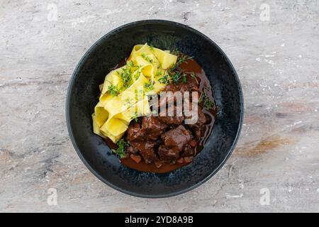 Tradizionale ragù di veleno brasato tedesco con verdure e tagliatelle in salsa dolce e piccante al cioccolato al vino rosso servito come vista dall'alto in un nordico Foto Stock