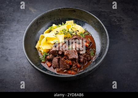 Ragù di cervo tradizionale tedesco brasato con verdure e tagliatelle in salsa dolce e piccante al cioccolato al vino rosso servito come primo piano in un nordico Foto Stock