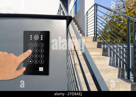 Mano utilizzando la tastiera del moderno sistema di sicurezza vicino alle scale Foto Stock