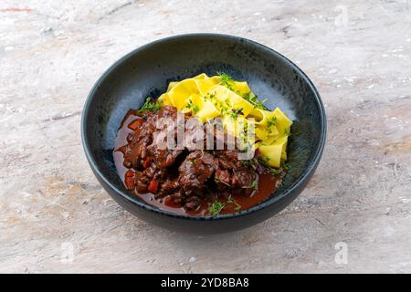 Ragù di cervo tradizionale tedesco brasato con verdure e tagliatelle in salsa dolce e piccante al cioccolato al vino rosso servito come primo piano in un nordico Foto Stock