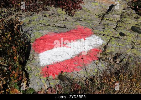Waymark con bandiera austriaca, dipinto su una massiccia formazione rocciosa vicino a Serfaus Foto Stock
