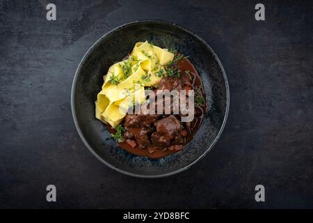 Tradizionale ragù di veleno brasato tedesco con verdure e tagliatelle in salsa dolce e piccante al cioccolato al vino rosso servito come vista dall'alto in un nordico Foto Stock