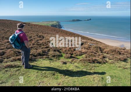 Uomo e vista di Rhossili e Worms Head da Rhossili Down, Gower, Galles, Regno Unito Foto Stock