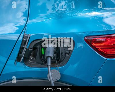 Un cavo di ricarica collegato a un veicolo elettrico per caricare la batteria in una stazione di ricarica pubblica. Foto Stock