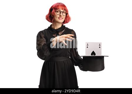 Maga con un cappello che esegue una trick magica con un asso isolato su sfondo bianco Foto Stock