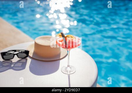 Una bevanda rossa in un elegante bicchiere con gambo lungo sul lato della piscina. Foto Stock