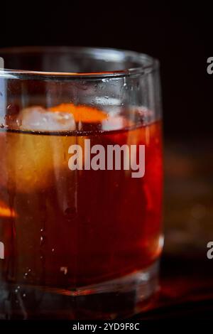 Cocktail alcolico Negroni o cocktail analcolico, bevanda con ghiaccio e scorza d'arancia come decorazione su tavolo di legno. Primo piano. Foto Stock