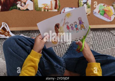 Creazione della bacheca di visione. Ragazza che taglia la foto sul pavimento, vista dall'alto Foto Stock