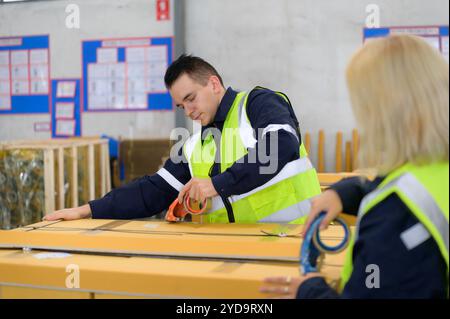 Gruppo di operai nel magazzino ricambi auto imballaggio di piccole parti in scatole dopo aver ispezionato le parti della vettura pronte per essere inviate al piano di assemblaggio della vettura Foto Stock