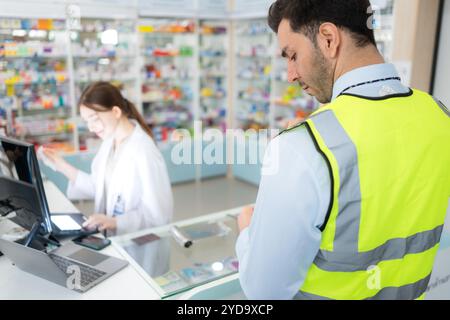 Il farmacista fornisce la medicina agli ingegneri che vengono a comprare la medicina in farmacia. Foto Stock