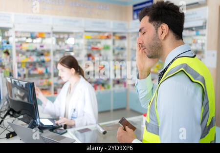 Il farmacista fornisce la medicina agli ingegneri che vengono a comprare la medicina in farmacia. Foto Stock