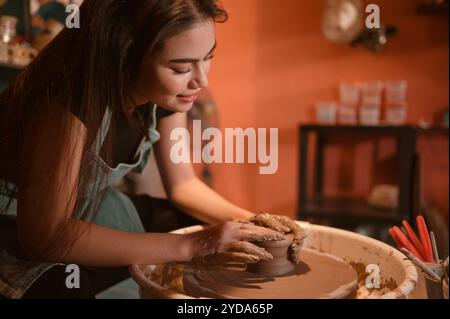 Artista di ceramica, giovane donna che crea un pezzo di argilla modellata con calma e meticolosamente per produrre l'opera più attraente Foto Stock