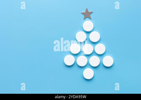 Collezione di tavolette bianche che formano l'albero di Natale con la stella sulla parte superiore, sfondo azzurro. Miscela unica di salute e spirito natalizio, farmaceutico Foto Stock