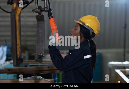 Tecnici femminili che ispezionano e testano il funzionamento delle gru di sollevamento in impianti industriali pesanti. Foto Stock