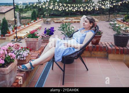 La giovane donna con il vetro in mano riposa sulla terrazza di casa. Foto Stock