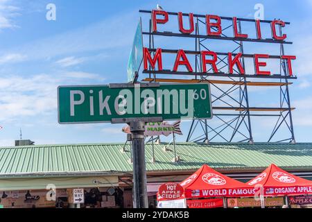 Seattle, Washington, USA - 19 settembre 2024: Cartello con il nome della strada Pike Place in verde con il cartello rosso al neon del mercato pubblico sullo sfondo di Seattle Foto Stock