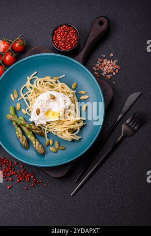 Colazione deliziosa e abbondante, con uova in camicia su pane tostato con formaggio spalmabile e asparagi Foto Stock