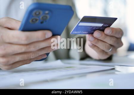 Uomo asiatico che paga con carta di credito su smartphone in ufficio. Uomo che usa smartphone per lo shopping portafoglio elettronico online Foto Stock