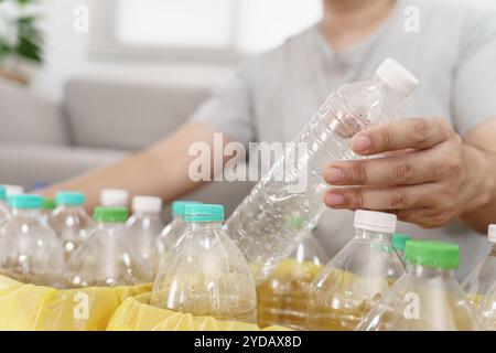 Casa riciclare eco-green zero Concept uomo che lancia bottiglie di plastica vuote in un cestino con sacchetti per rifiuti gialli a casa Foto Stock