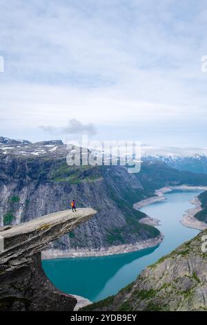 Una solitaria camminata sulla scogliera di Trolltunga in Norvegia ammira l'aspra bellezza delle montagne e dei fiordi che si estendono sotto, Trolltunga, Norvegia, donne asiatiche Foto Stock