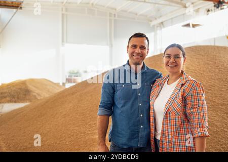 Una giovane coppia sposata sta sorridendo in un granaio. Una donna affascinante e un uomo attraente in abiti casual in una fattoria in un whea Foto Stock