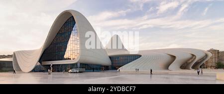 Baku, Azerbaigian - 11 maggio 2024: Il centro Heydar Aliyev mette in mostra il suo design fluido unico e le sue linee angolari sorprendenti, inondato dalla calda luce del tramonto Foto Stock