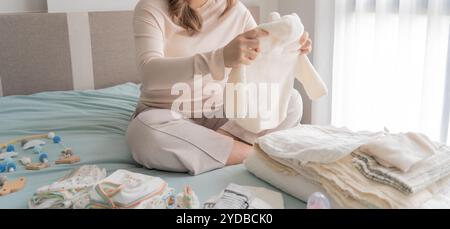 Donna asiatica incinta che si prepara per l'ospedale di maternità preparando e pianificando vestiti per neonati per nuovo babyÂ di gravidanza pac Foto Stock