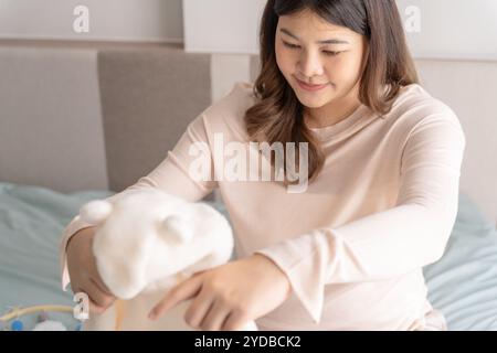 Donna asiatica incinta che si prepara per l'ospedale di maternità preparando e pianificando vestiti per neonati per nuovo babyÂ di gravidanza pac Foto Stock