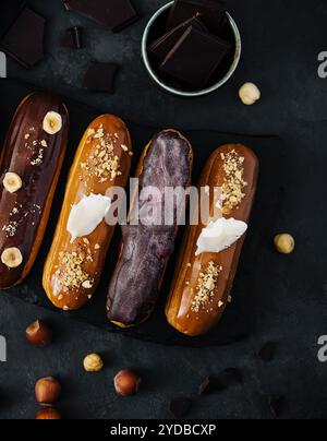 Dolci eclari di cioccolato su tavola di legno nera Foto Stock