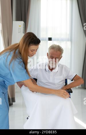 Il medico indossa una coperta per riscaldarsi e parla con un paziente anziano con depressione. nel soggiorno della casa Foto Stock