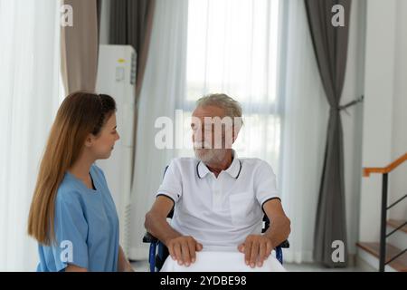 Il medico indossa una coperta per riscaldarsi e parla con un paziente anziano con depressione. nel soggiorno della casa Foto Stock