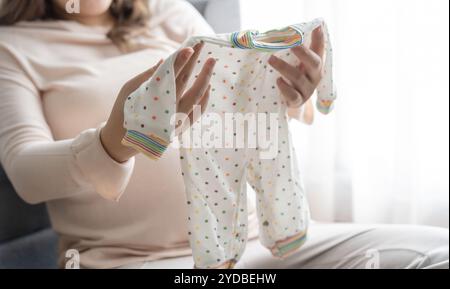 Donna asiatica incinta che si prepara per l'ospedale di maternità preparando e pianificando vestiti per neonati per nuovo babyÂ di gravidanza pac Foto Stock