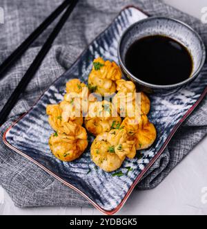 Gnocchi fritti con maiale ed erbe aromatiche sul piatto con salsa di soia Foto Stock