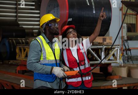 Due tecnici che ispezionano e testano il funzionamento delle gru di sollevamento in impianti industriali pesanti. Foto Stock