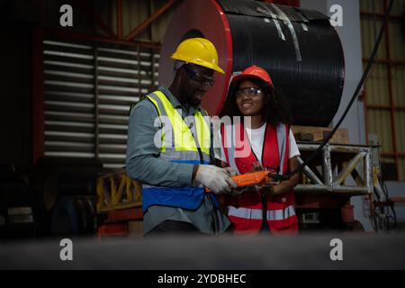 Due tecnici che ispezionano e testano il funzionamento delle gru di sollevamento in impianti industriali pesanti. Foto Stock