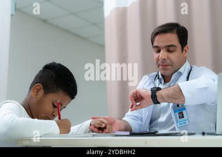 Un medico in un ospedale internazionale che cerca di controllare un bambino malizioso Foto Stock