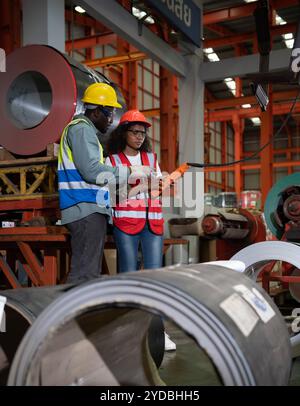 Due tecnici che ispezionano e testano il funzionamento delle gru di sollevamento in impianti industriali pesanti. Foto Stock