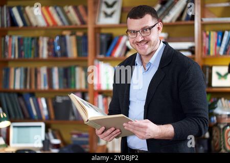 Libro di lettura dell'uomo nella biblioteca dell'università molti libri su uno sfondo Foto Stock