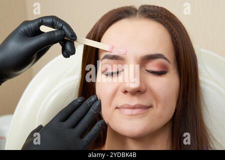 Bella ragazza che viene cerata in un salone di bellezza Foto Stock