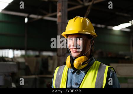 Il capo ingegnere meccanico che lavora in una fabbrica meccanica effettua il controllo delle comunicazioni radio con walkie-talkie e segue i tecnici asiatici che Foto Stock