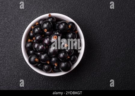 Bacche di ribes nero mature in gocce d'acqua in un recipiente di ceramica Foto Stock