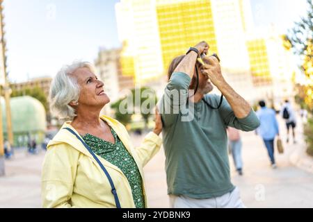 Uomo anziano che parla una foto con una fotocamera digitale mentre visita la città con il suo partner Foto Stock